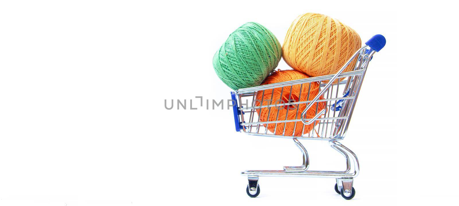 Trolley with yarn for knitting. Yarn for crocheting. Design of the embroidery section. Needlework. Hobbies and recreation. Colored threads on a white background. Isolated objects. Copy space