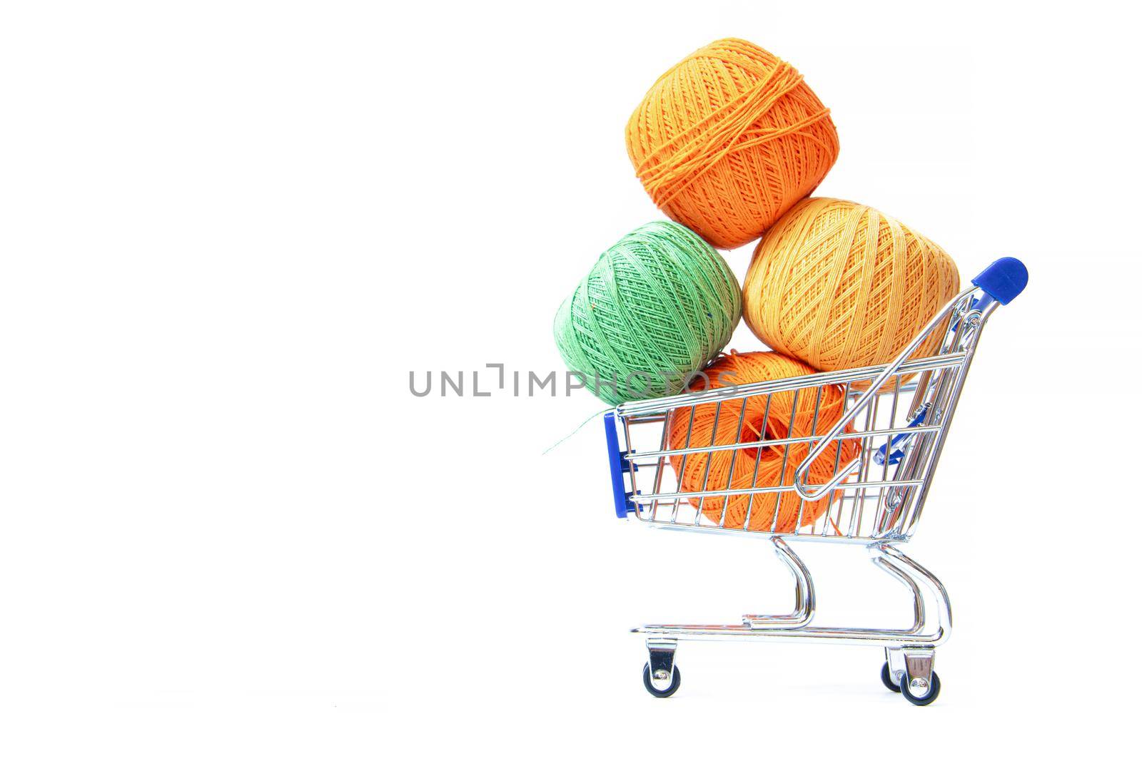 Trolley with yarn for knitting. Yarn for crocheting. Design of the embroidery section. Needlework. Hobbies and recreation. Colored threads on a white background. Isolated objects. Copy space