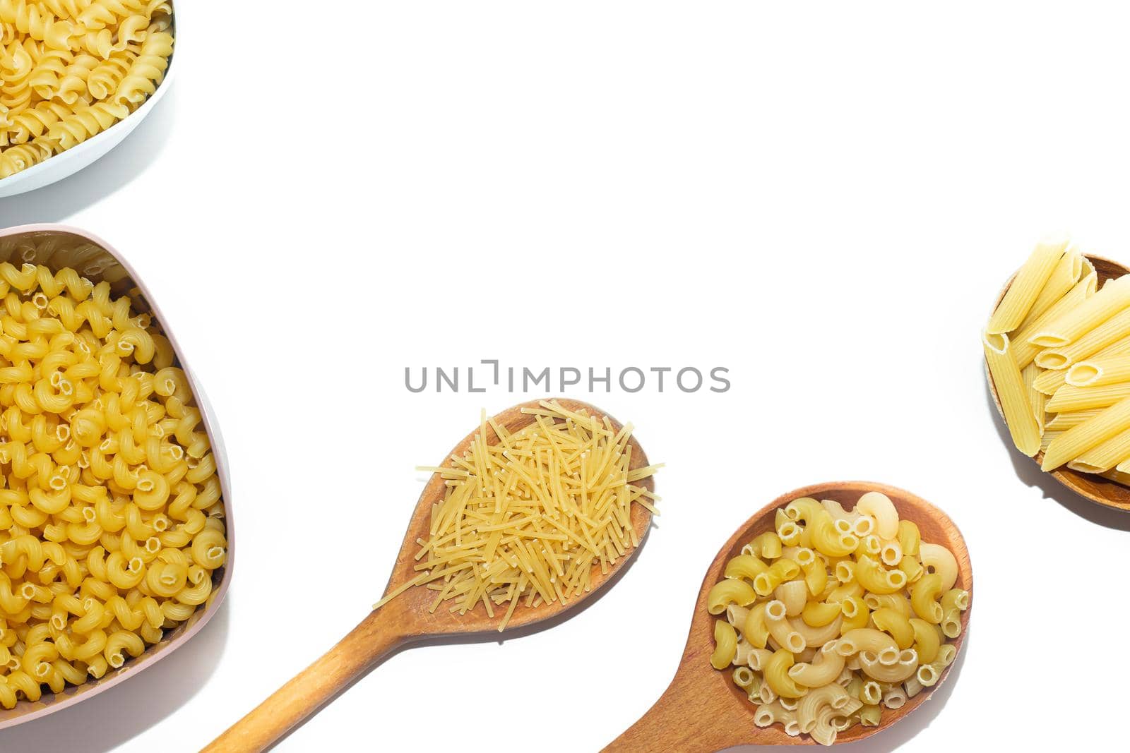 Macaroni several types in wooden spoons on a white background . Macaroni on wooden spoons . Macaroni on a white background. Article about the choice of pasta. Ingredients for the dish. Copy space . Isolated background. Food supply