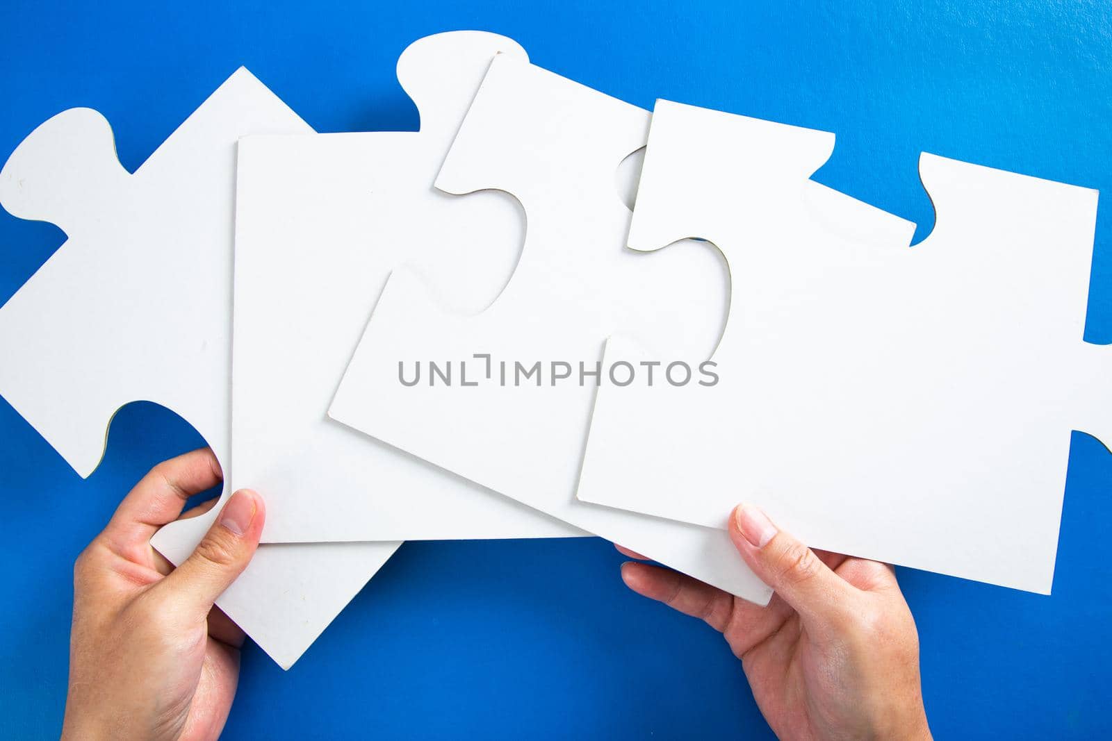 man hands holding big paper white blank puzzles on a blue background, concept of business by tehcheesiong