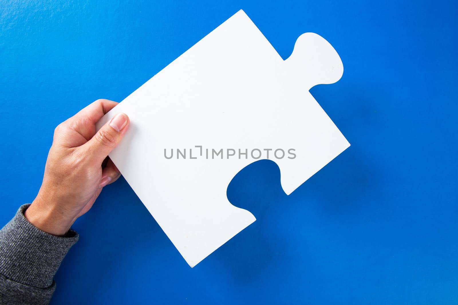 hands holding big paper white blank puzzles on a blue background, concept of business