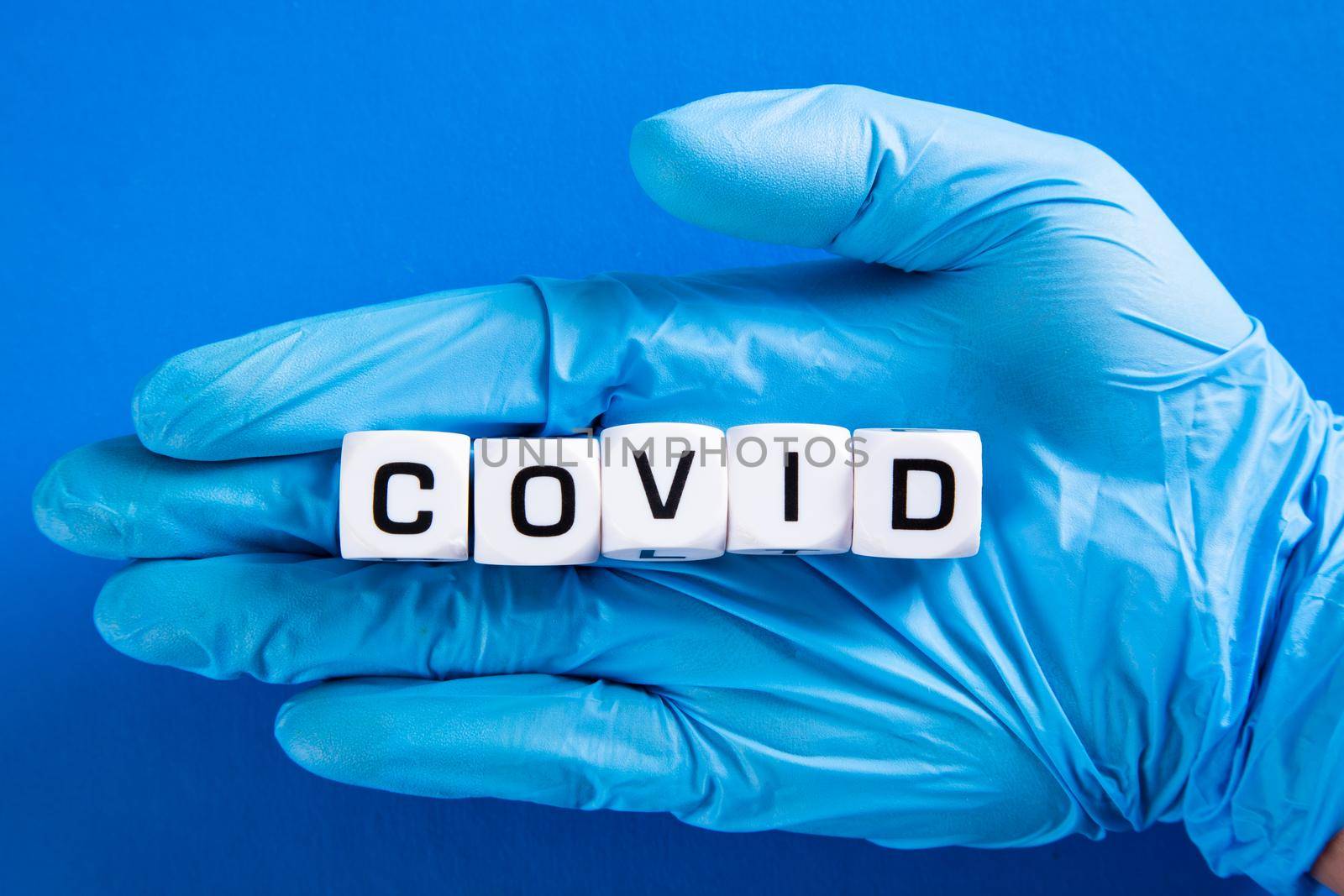 Hand in blue glove with Covid word. Medical and COVID-19 pandemic concept.