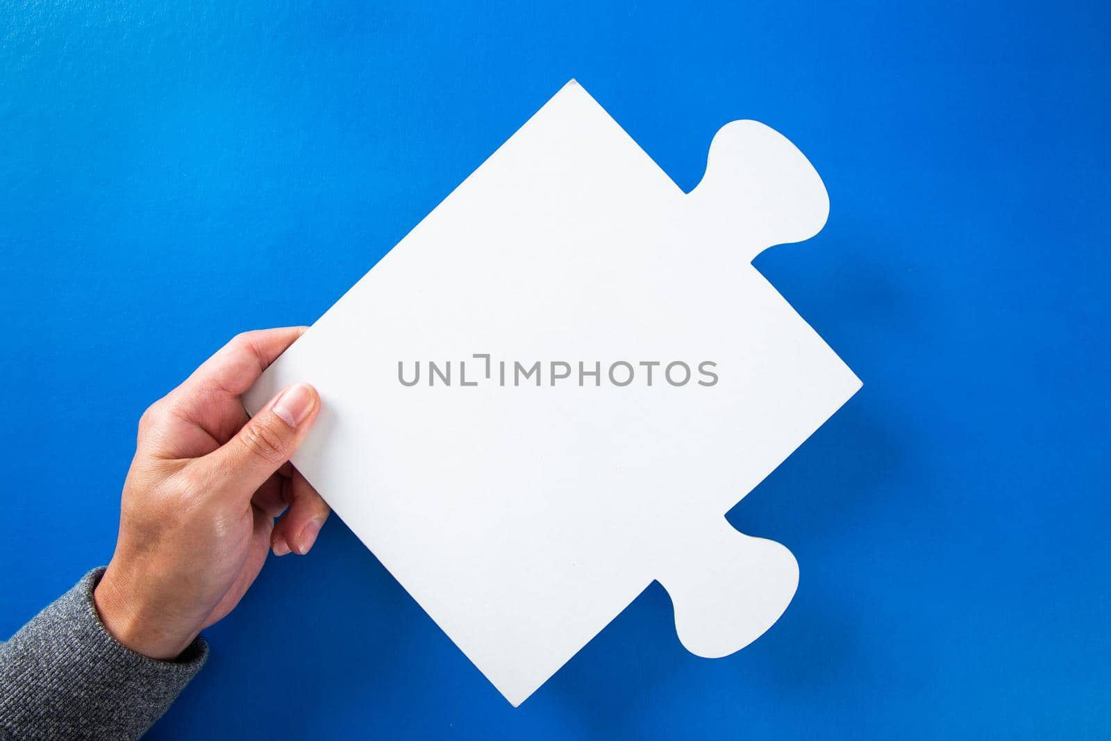 man hands holding big paper white blank puzzles on a blue background, concept of business by tehcheesiong
