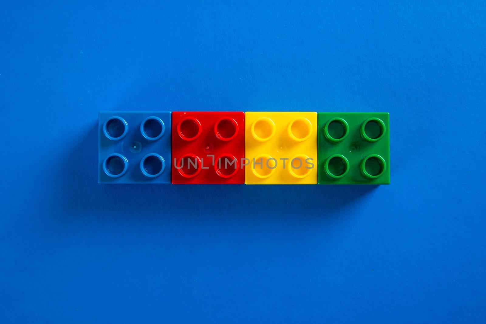 Color plastic building blocks on blue background by tehcheesiong