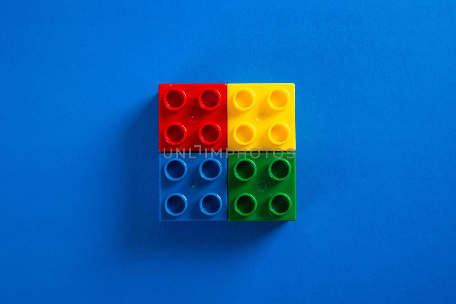 Color plastic building blocks on blue background by tehcheesiong