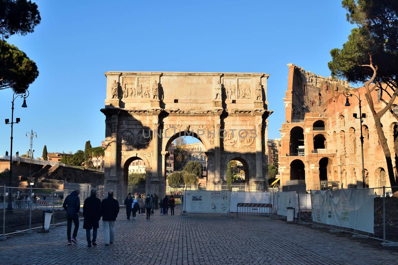 Rome, Italy - December 13th 2020: View of the Arch of Constantine and Coliseum with few tourists due to the Covid19 epidemic