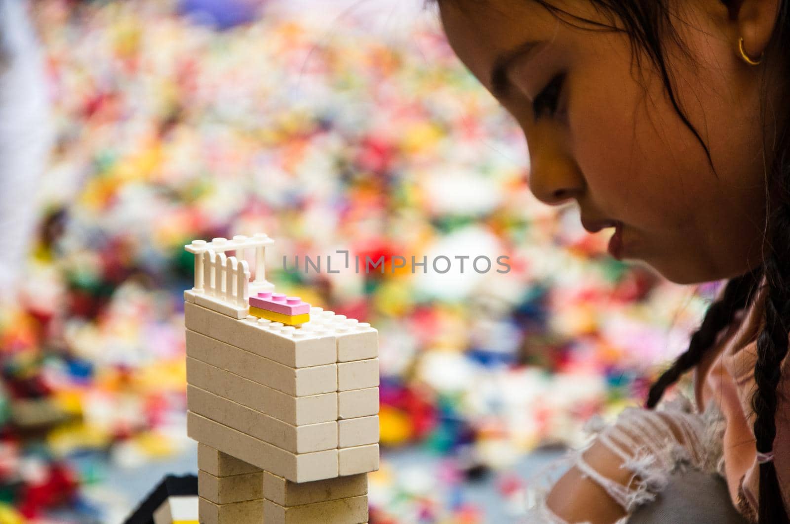 Little girl playing with colorful bricks at home or kindergarten. Closeup