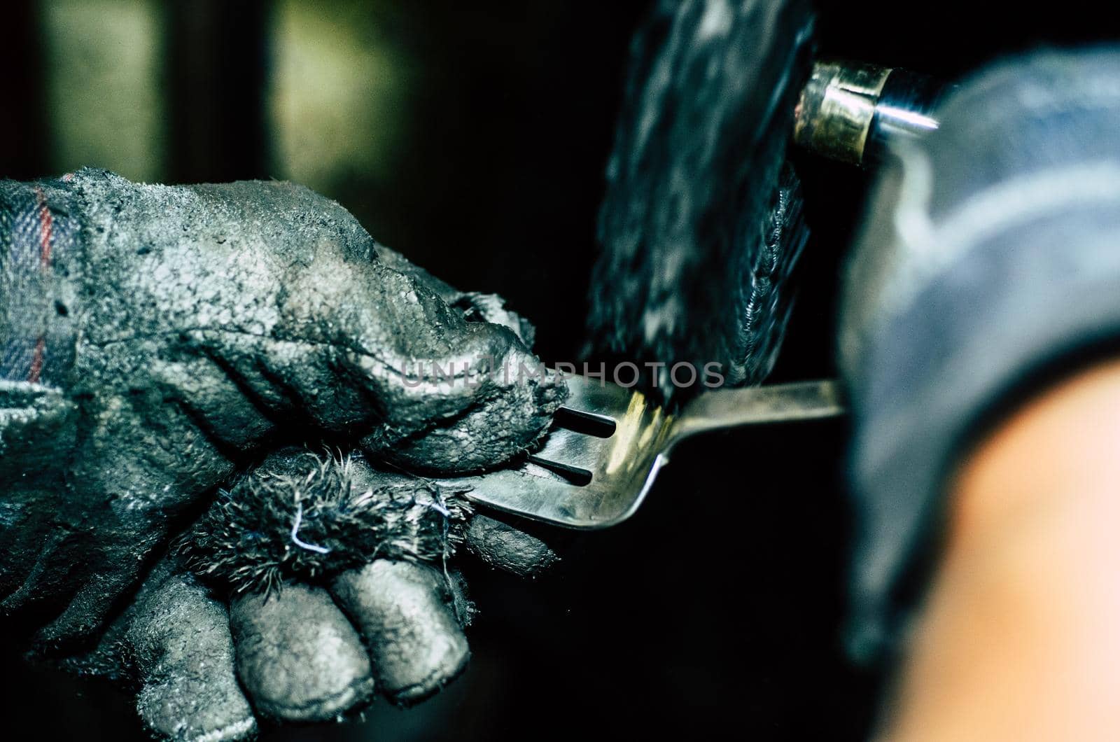 Jeweler working on silver fork in his workshop. Detail of silver polishing.