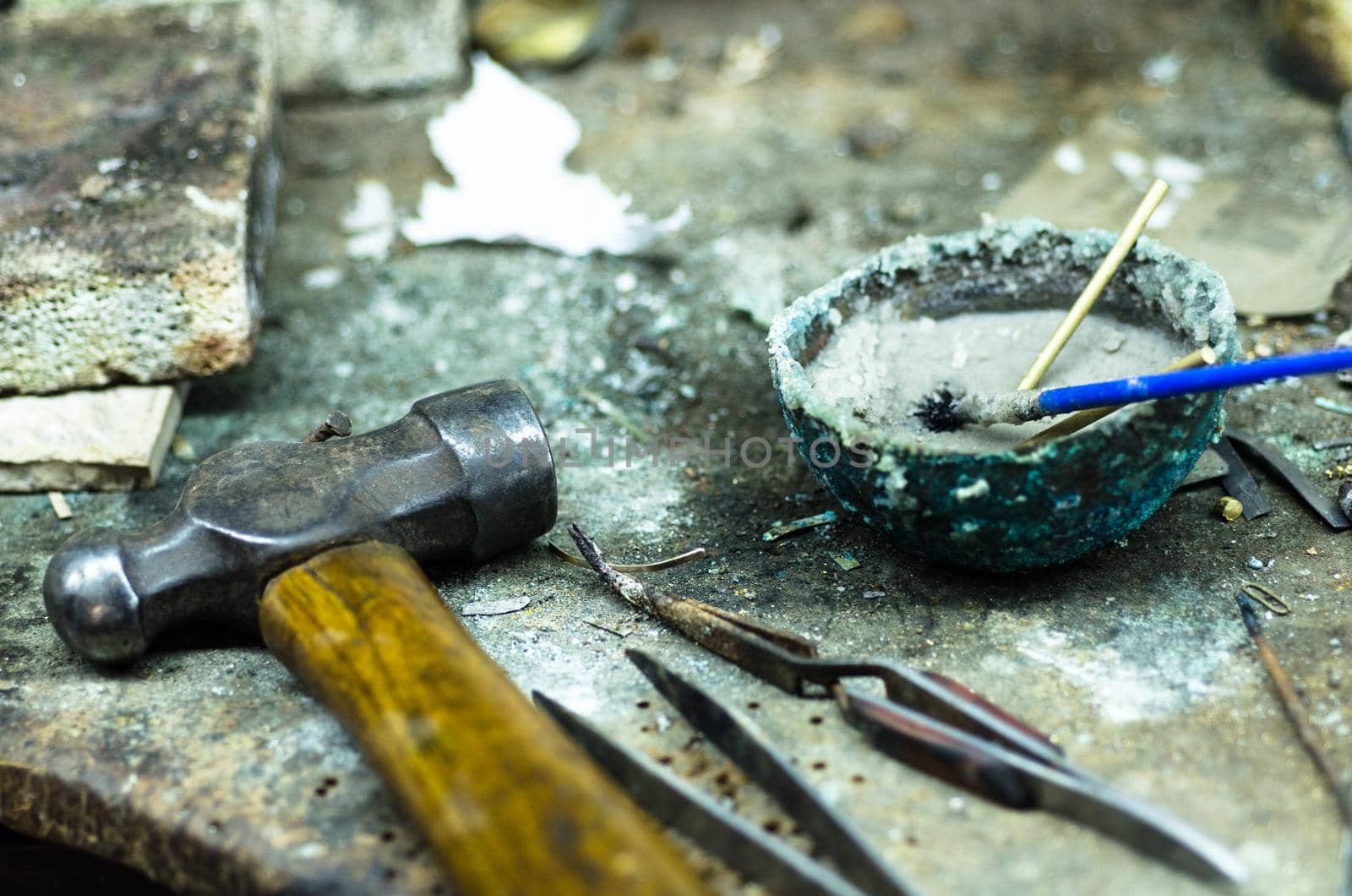 Top view of different goldsmiths tools on the jewelry workplace. Desktop for craft jewelry making with professional tools. Aerial view of tools over rustic wooden background.