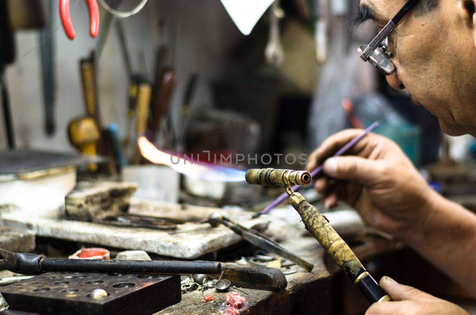 Master jeweler welding an ornament in a jewelry workshop. Image of hands and product close up.