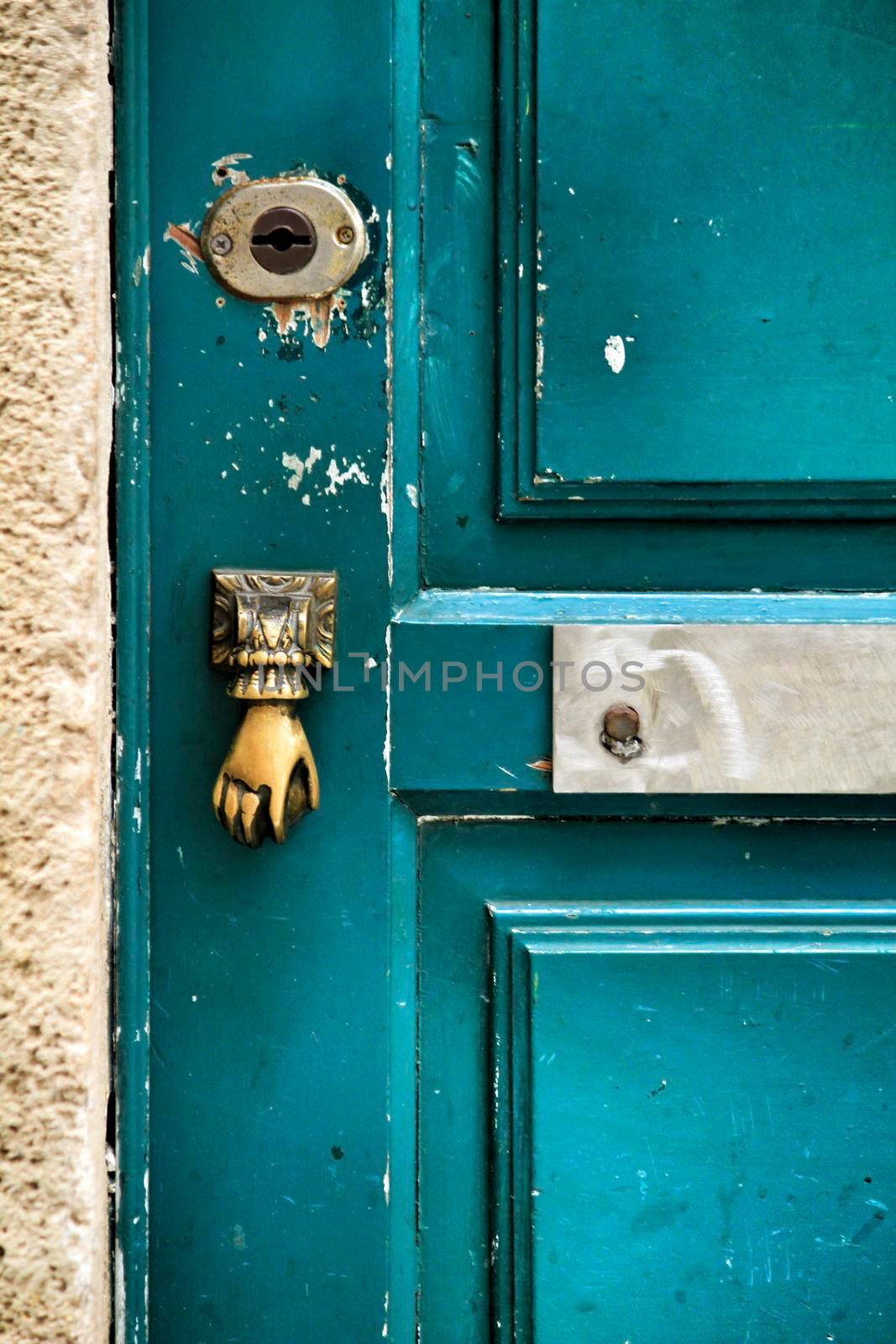 Old and colorful damaged wooden door with door knocker in Lisbon, Portugal.