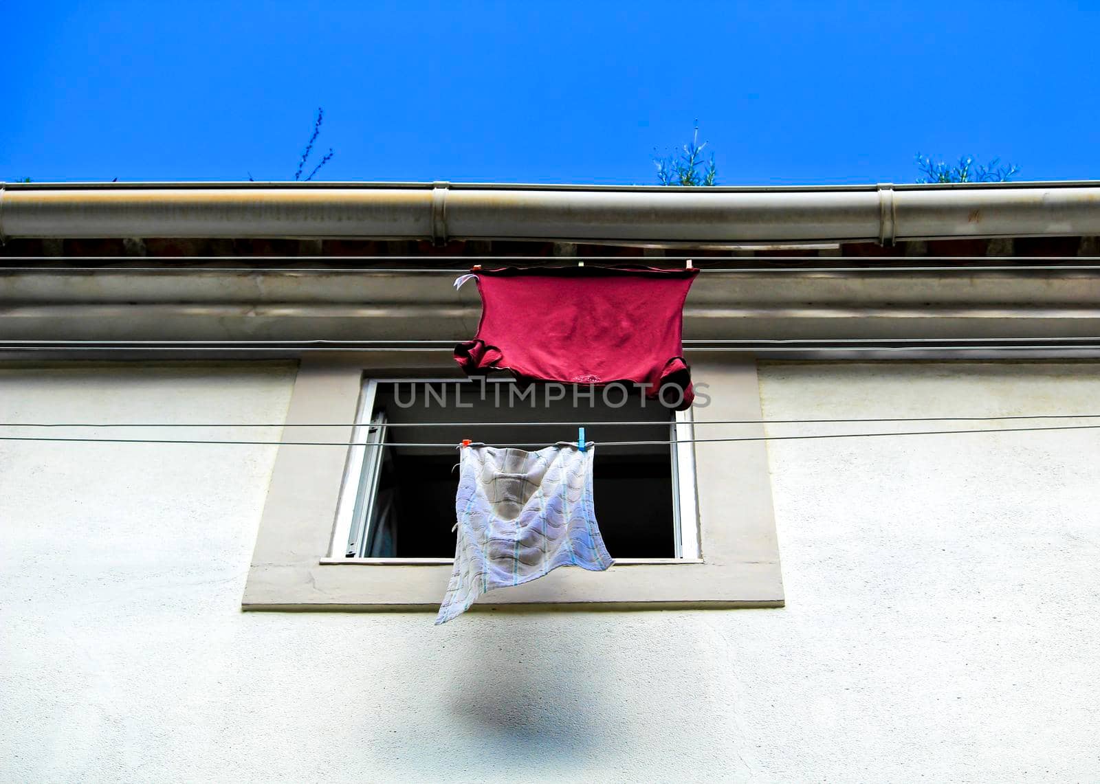 Old colorful typical facade in Lisbon with vintage wooden window and clothesline with hanging clothes
