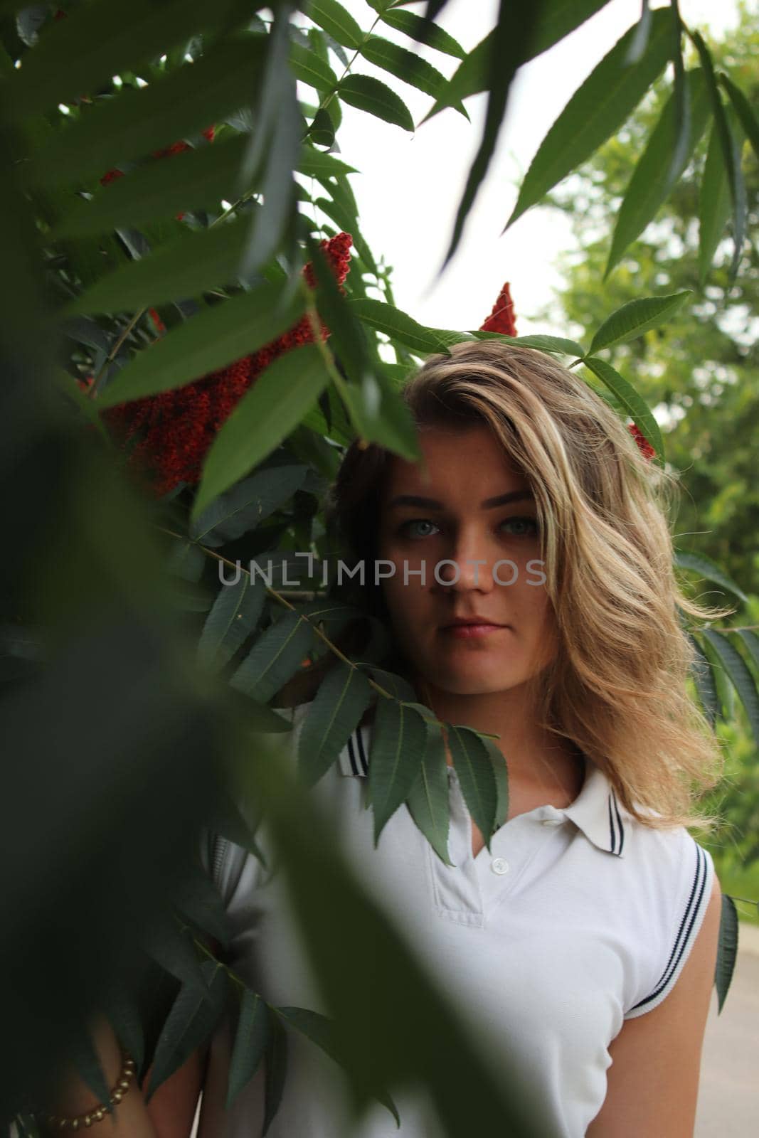 portrait of a flirty beautiful woman in white sport dress holding a tree branch in the tropical forest. Luxury resort by oliavesna