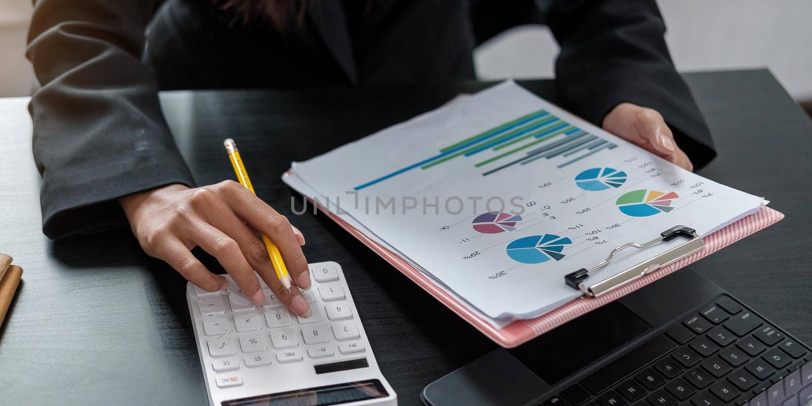 Woman with financial report and calculator. Woman using calculator to calculate report at the table in office by wichayada