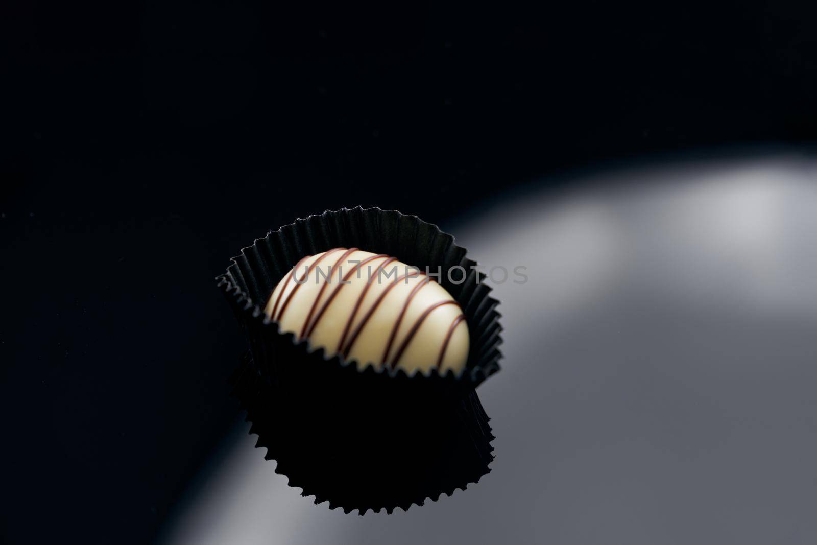 Single chocolate candy on glazed surface by SerhiiBobyk