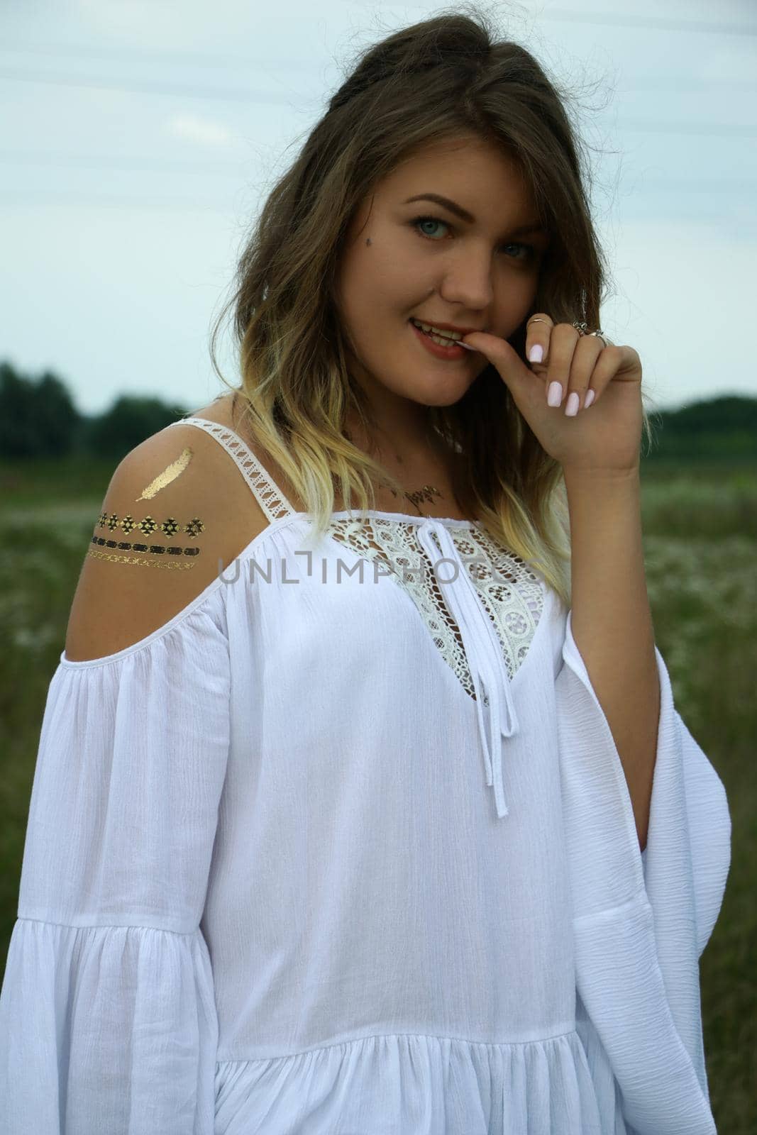 portrait of a happy flirty beautiful blonde woman in white blouse in the field. Temporary tattoo. Drawings on body. hippie. by oliavesna