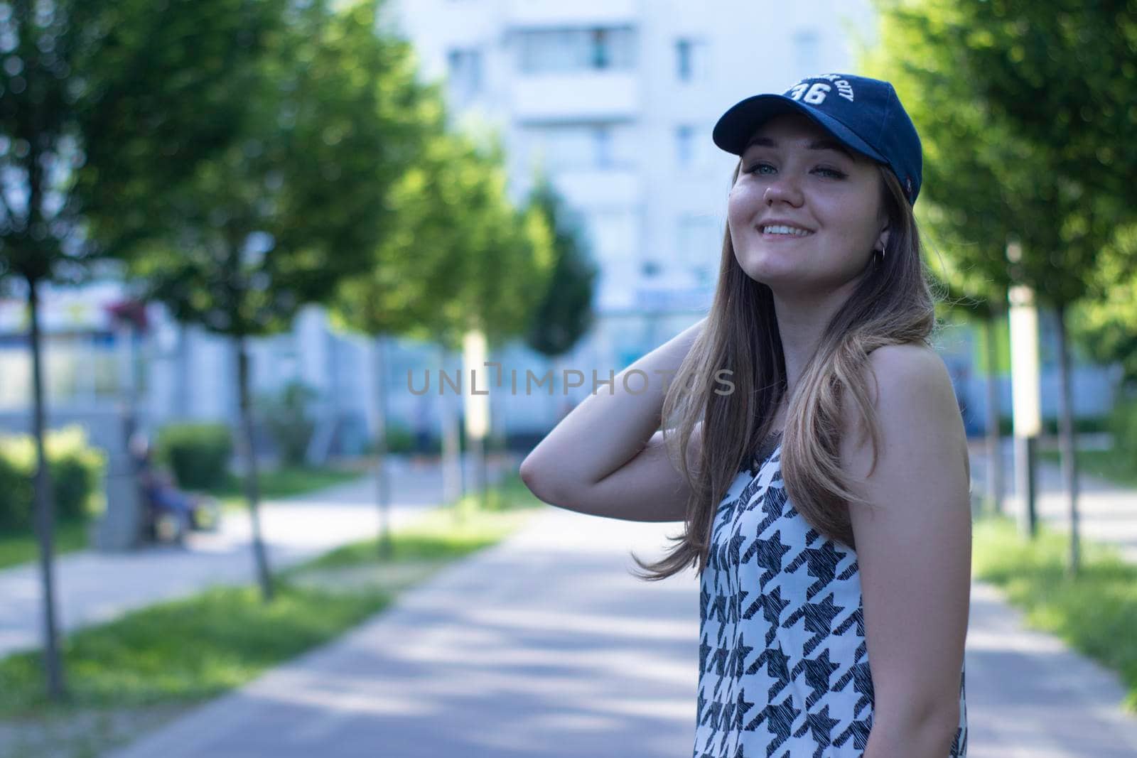 Pretty young blonde woman wearing a t-shirt, jeans shorts and cap. in a park. copy space. High quality photo