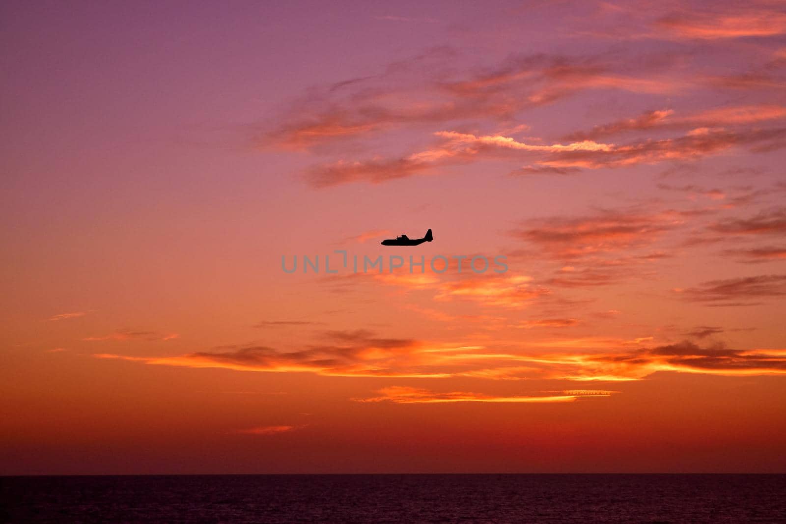 View of an airplane flying at sunset light. by silentstock639