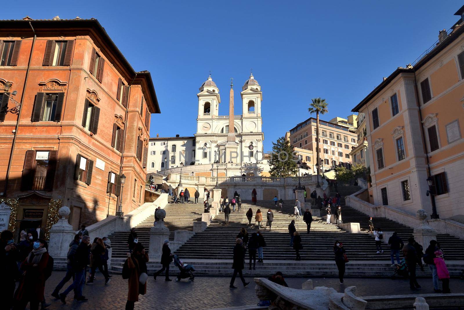 Rome, Italy - December 13th 2020: View of the Trinita dei Monti during the Covid-19 epidemic. Many people who wear protective face masks on their Christmas shopping stroll.