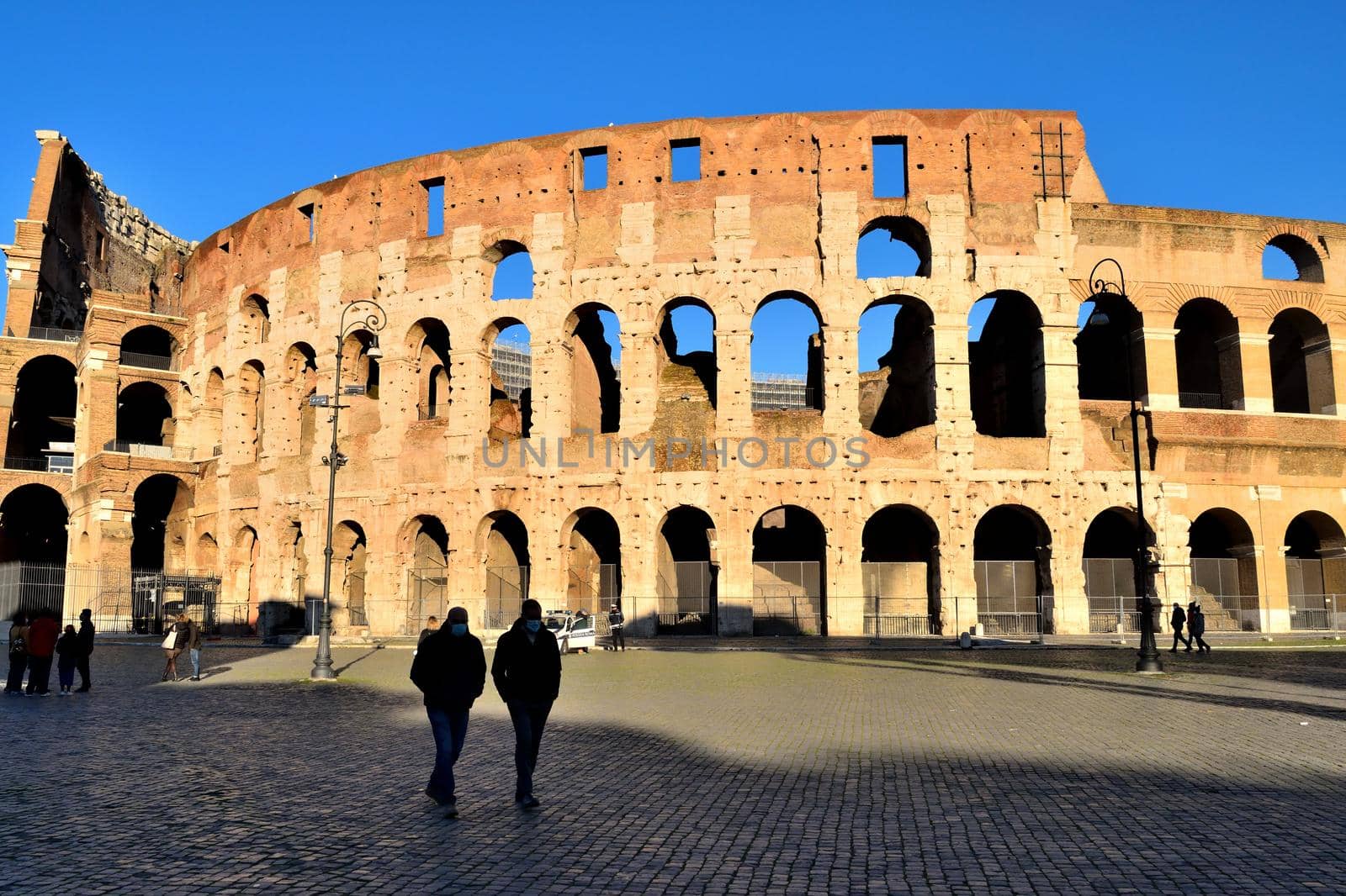 Rome, Italy - December 13th 2020: View of the Arch of Constantine and Coliseum with few tourists due to the Covid19 epidemic by silentstock639