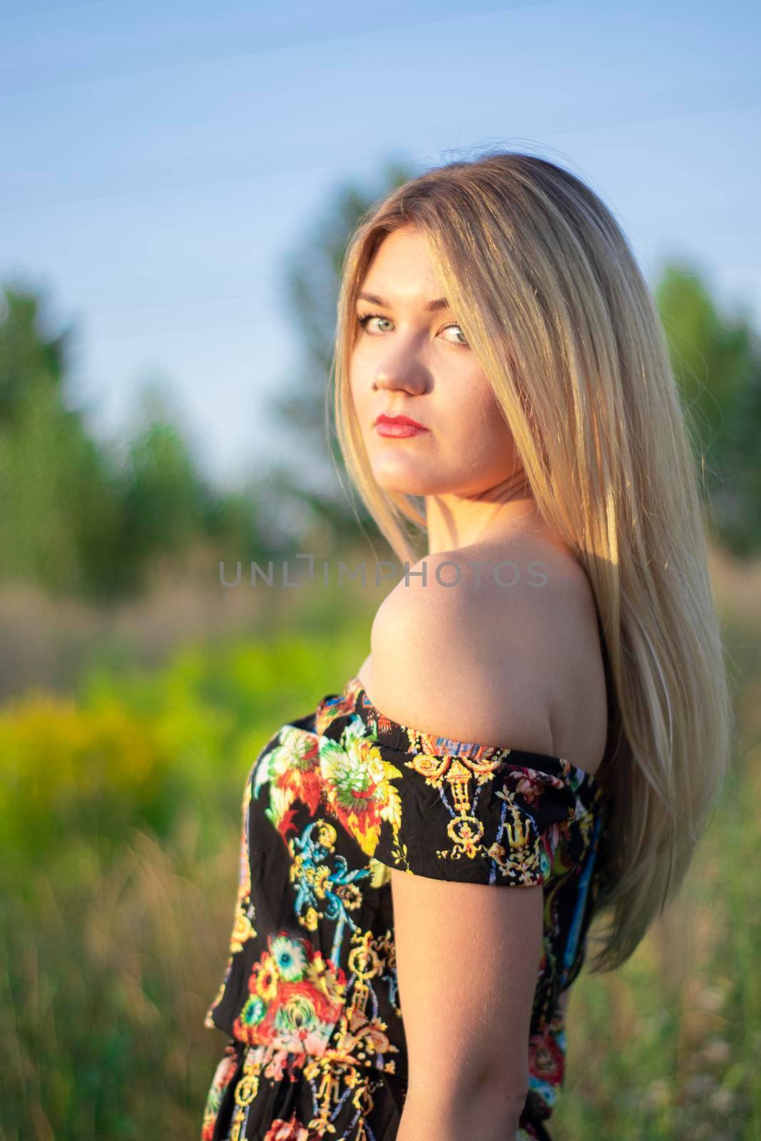 overlight bright portrait of a charming attractive blonde in flowery dress in the field by oliavesna