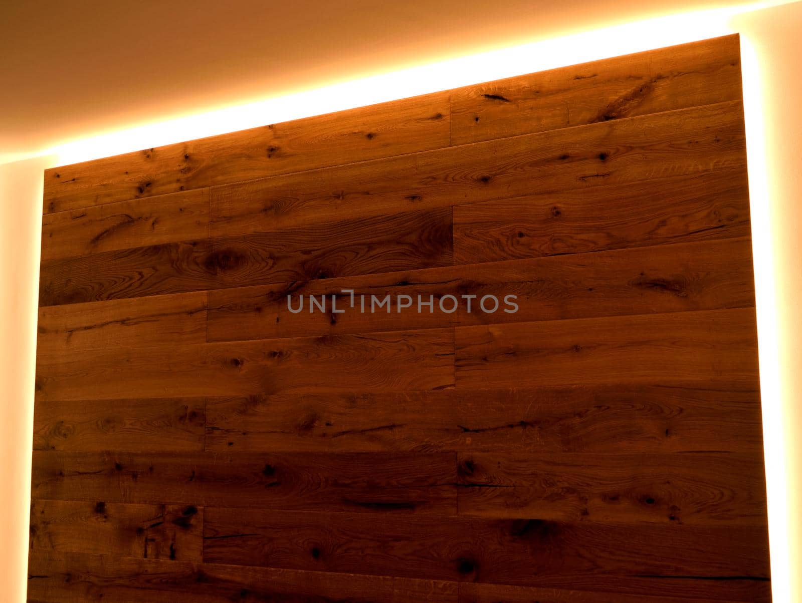 Closeup of a wall covered with parquet with its natural veins, delimited by LED strips. by silentstock639