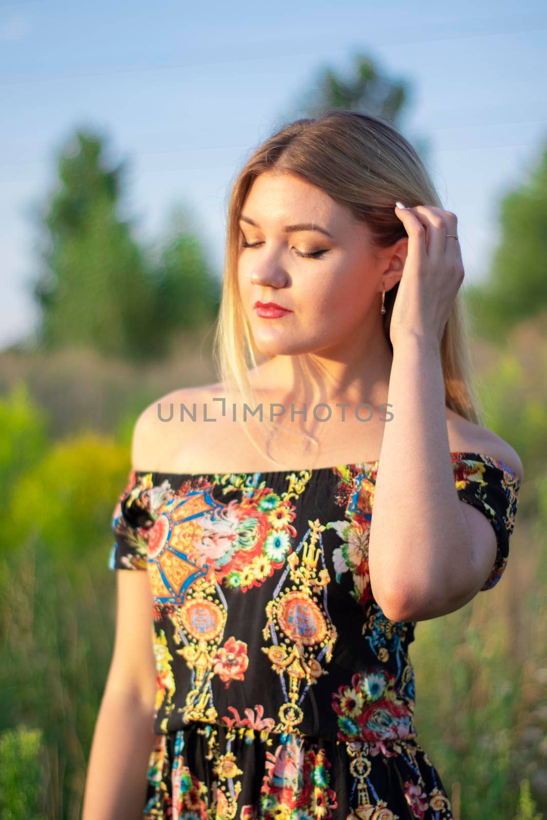 overlight bright portrait of a charming attractive blonde in flowery dress in the field by oliavesna