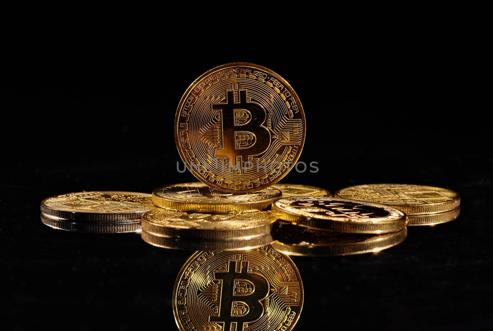 Leader in cryptocurrency Bitcoin BTC on a top of coins against black mirror surface. Closeup golden coin with bitcoin logo. А heap of decentralized digital currency. Crypto payment. Electronic money.