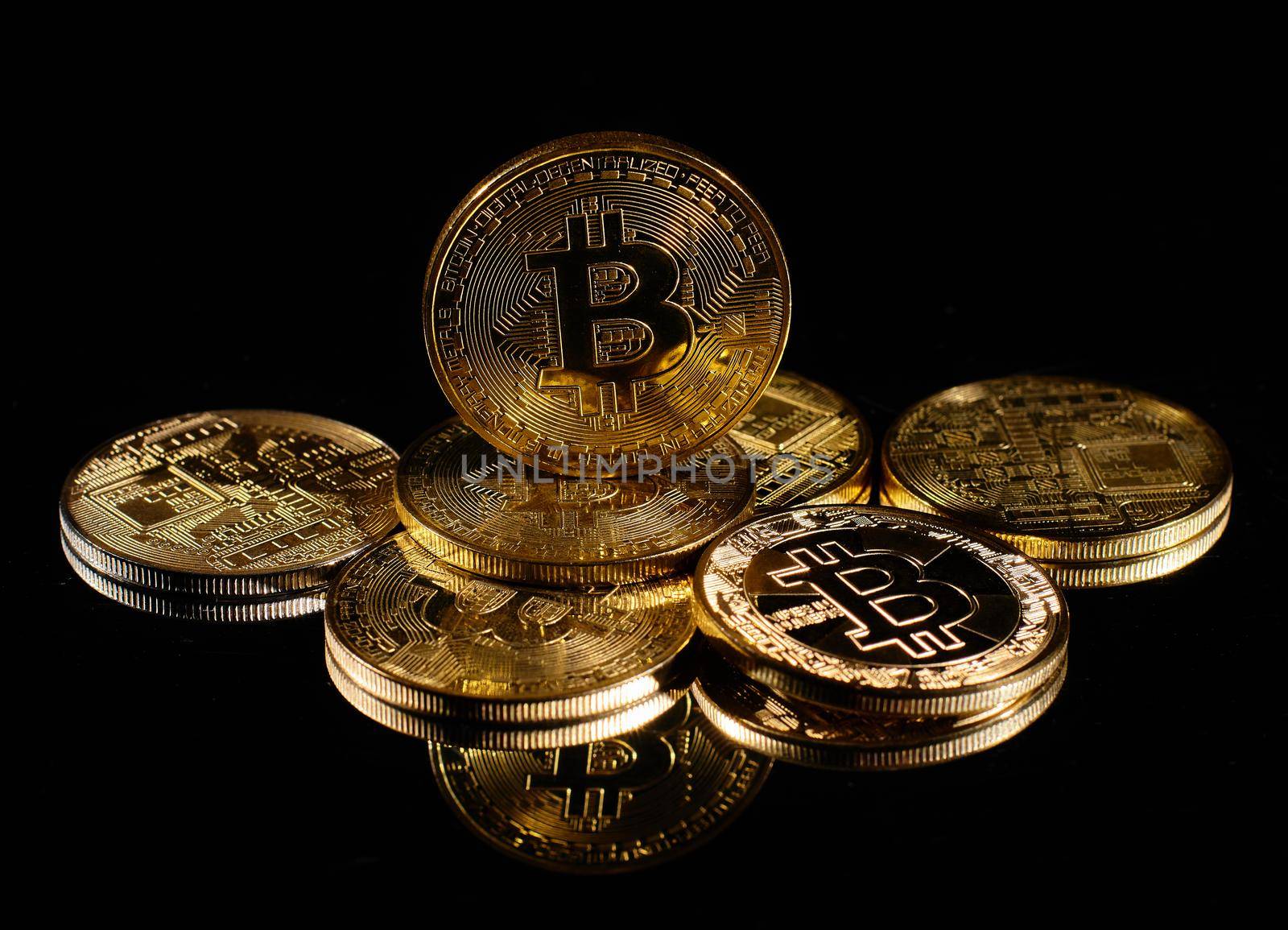 Leader in cryptocurrency Bitcoin BTC on a top of coins against black mirror surface. Closeup golden coin with bitcoin logo. А heap of decentralized digital currency. Crypto payment. Electronic money.