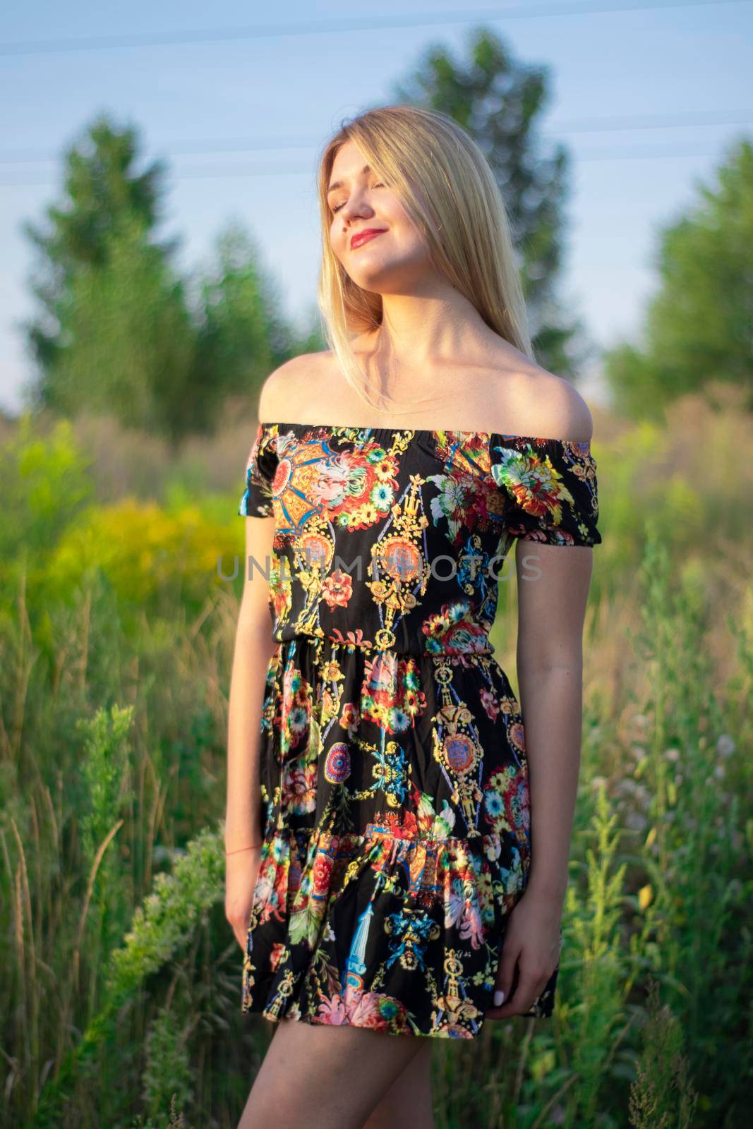 overlight bright portrait of a charming attractive blonde in flowery dress in the field by oliavesna