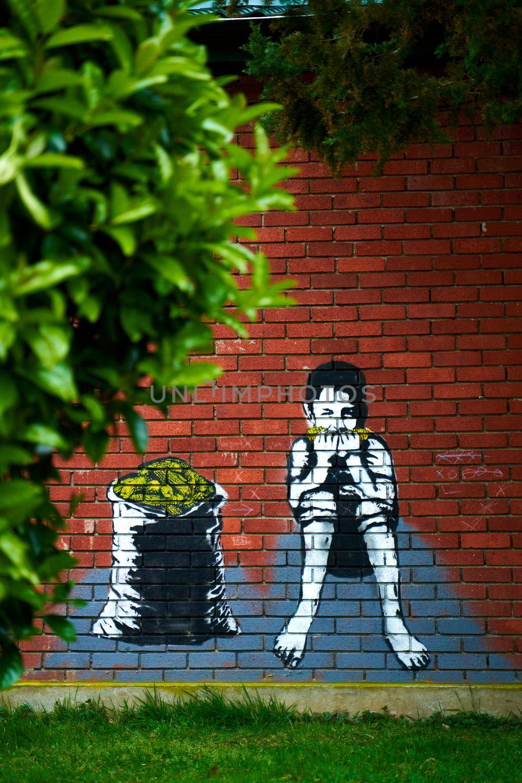 Graffiti drawing on a brick wall. A boy eats corn while sitting near a sack full of corn.