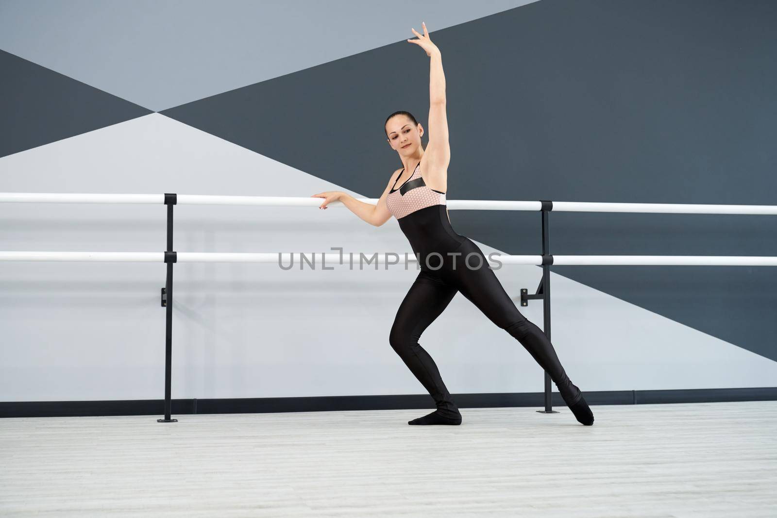 Female dancer training in big hall with handrails. by SerhiiBobyk