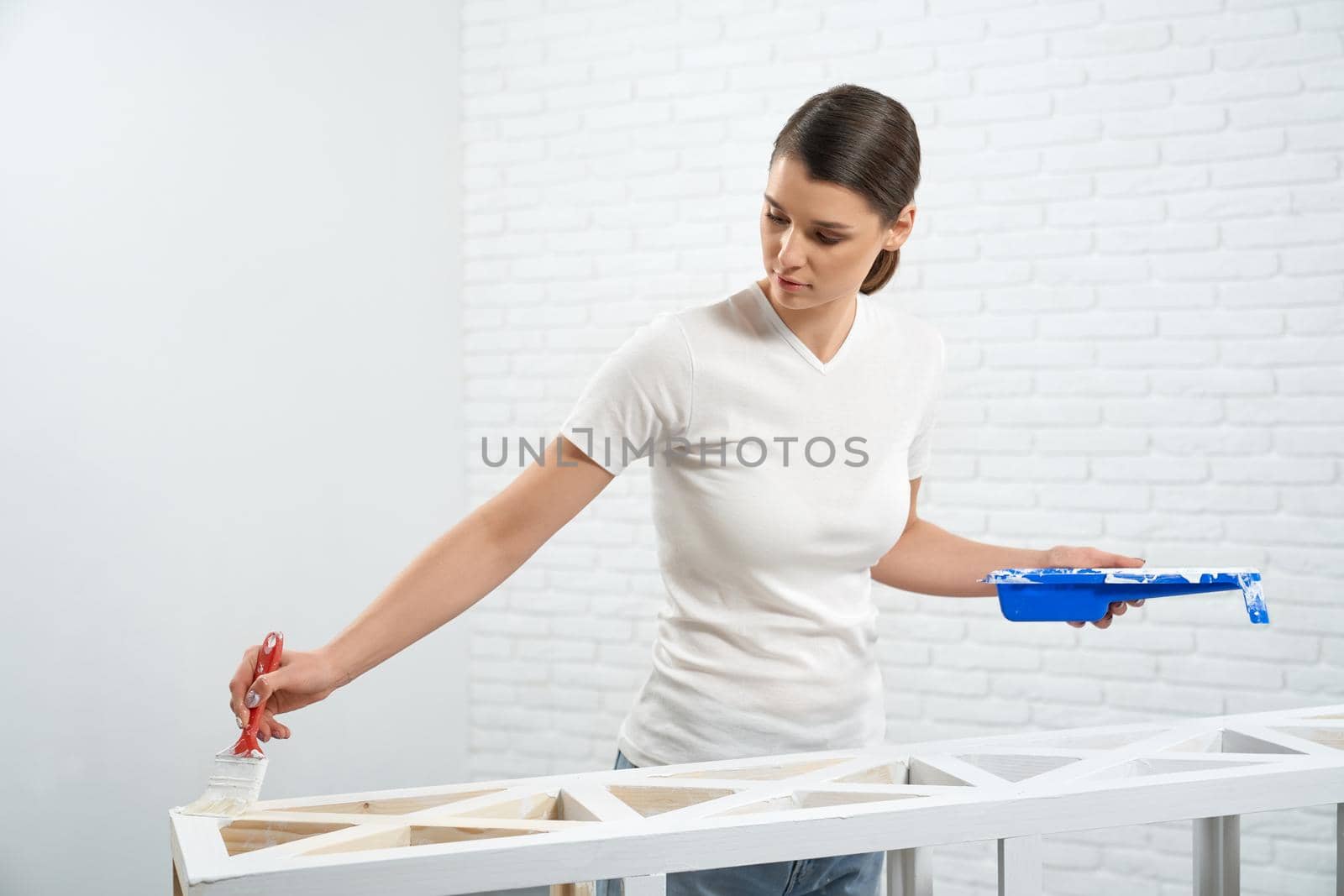 Young woman painting rack in white color. by SerhiiBobyk