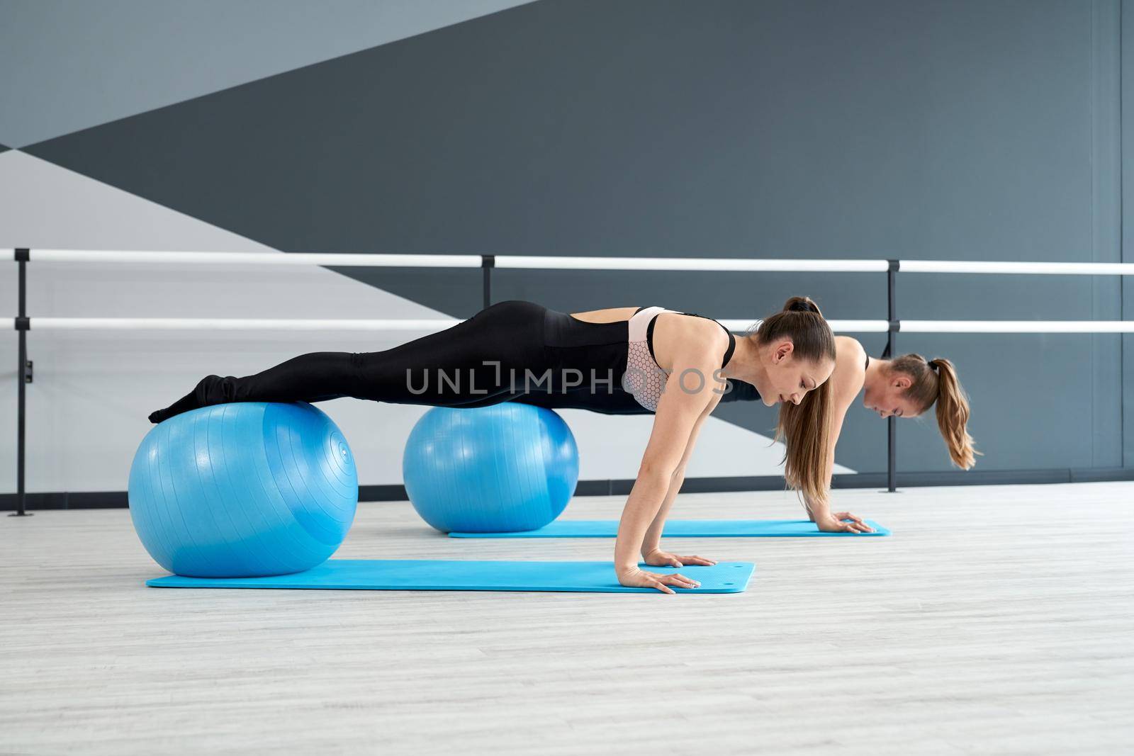 Women practicing plank position using fitness balls. by SerhiiBobyk