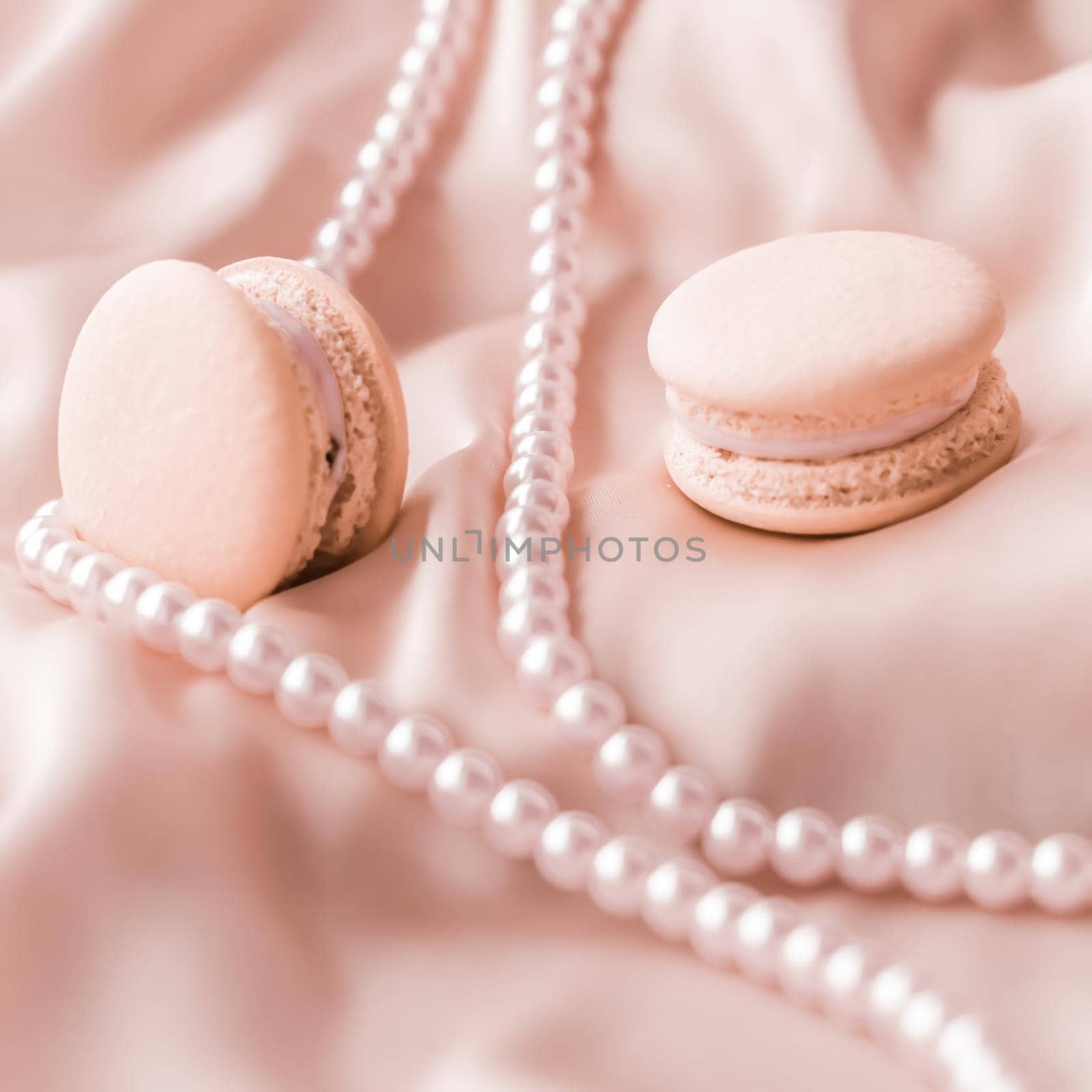 Girly, bakery and branding concept - Sweet macaroons and pearls jewellery on silk background, parisian chic jewelry, French dessert food and cake macaron for luxury confectionery brand, holiday gift