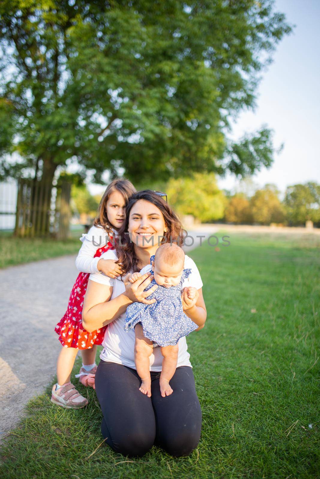 Happy woman and her daughters playing on the grass by Kanelbulle