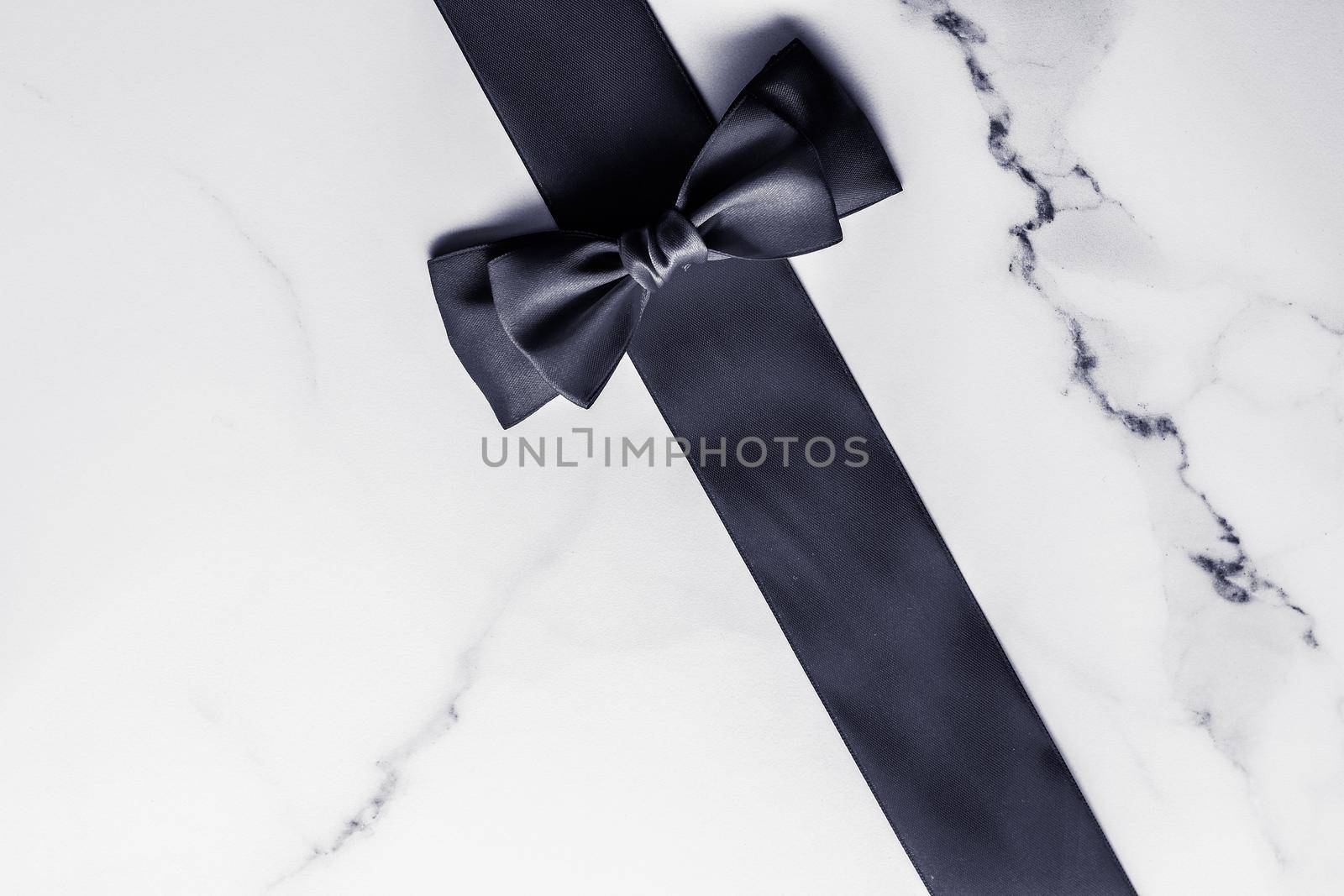 Holiday gift, decoration and sale promotion concept - Black silk ribbon and bow on marble background, flatlay