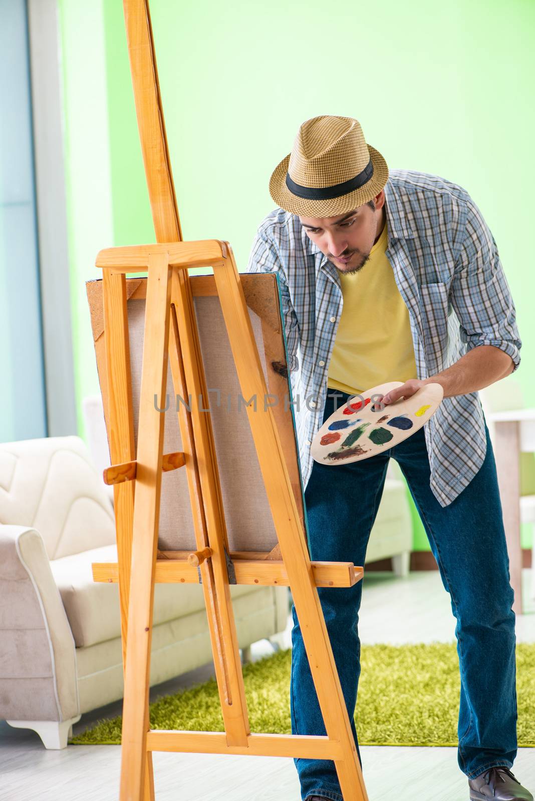 Young male artist working on new painting in his studio
