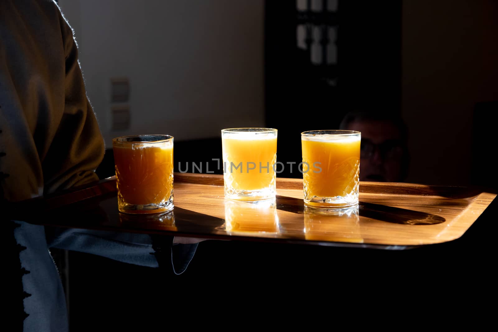 Orange juice in glasses being served on tray backlit by sun in Marrakech Morocco by kgboxford