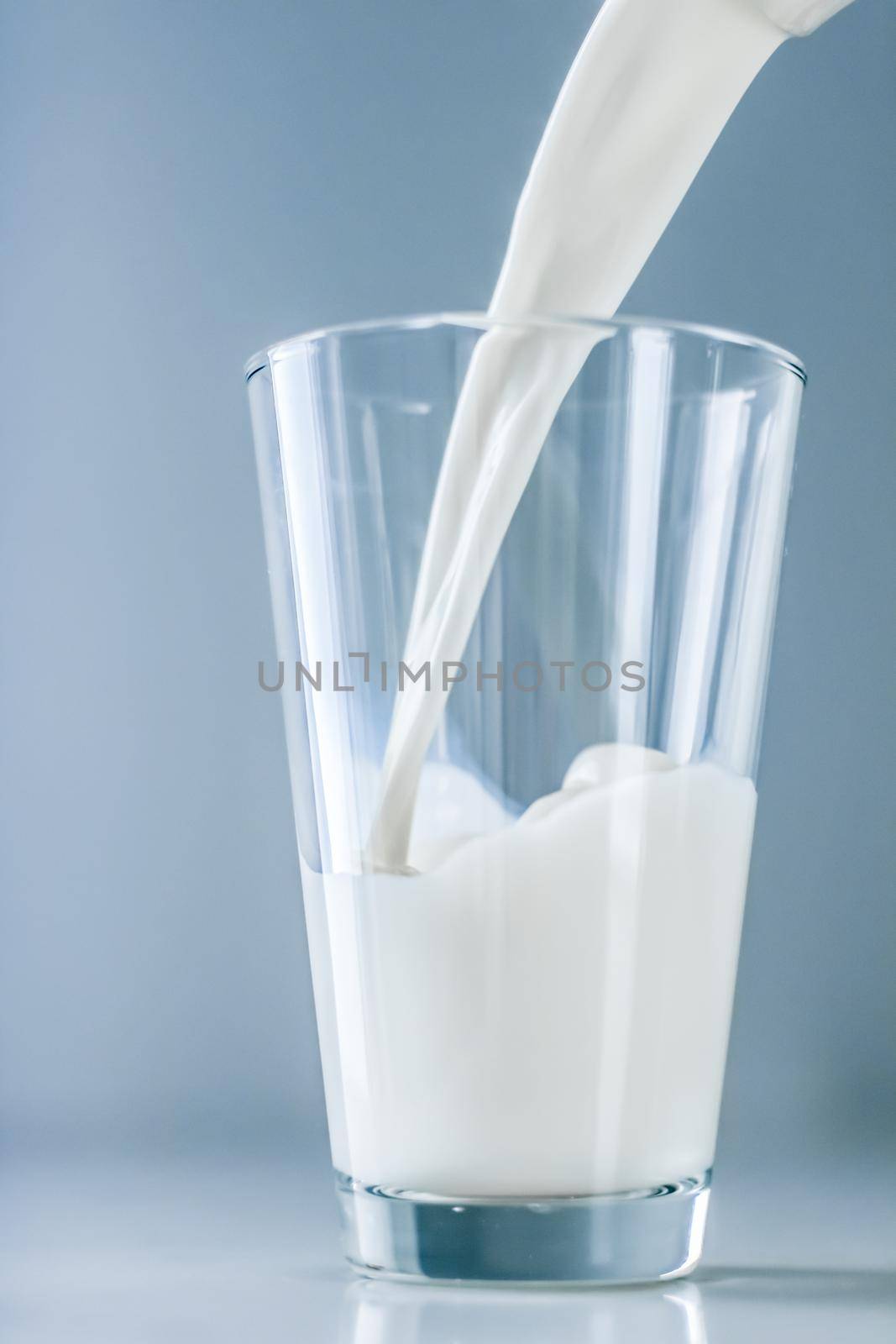 Dairy, healthy nutrition and breakfast concept - World Milk Day, pouring into glass on marble table