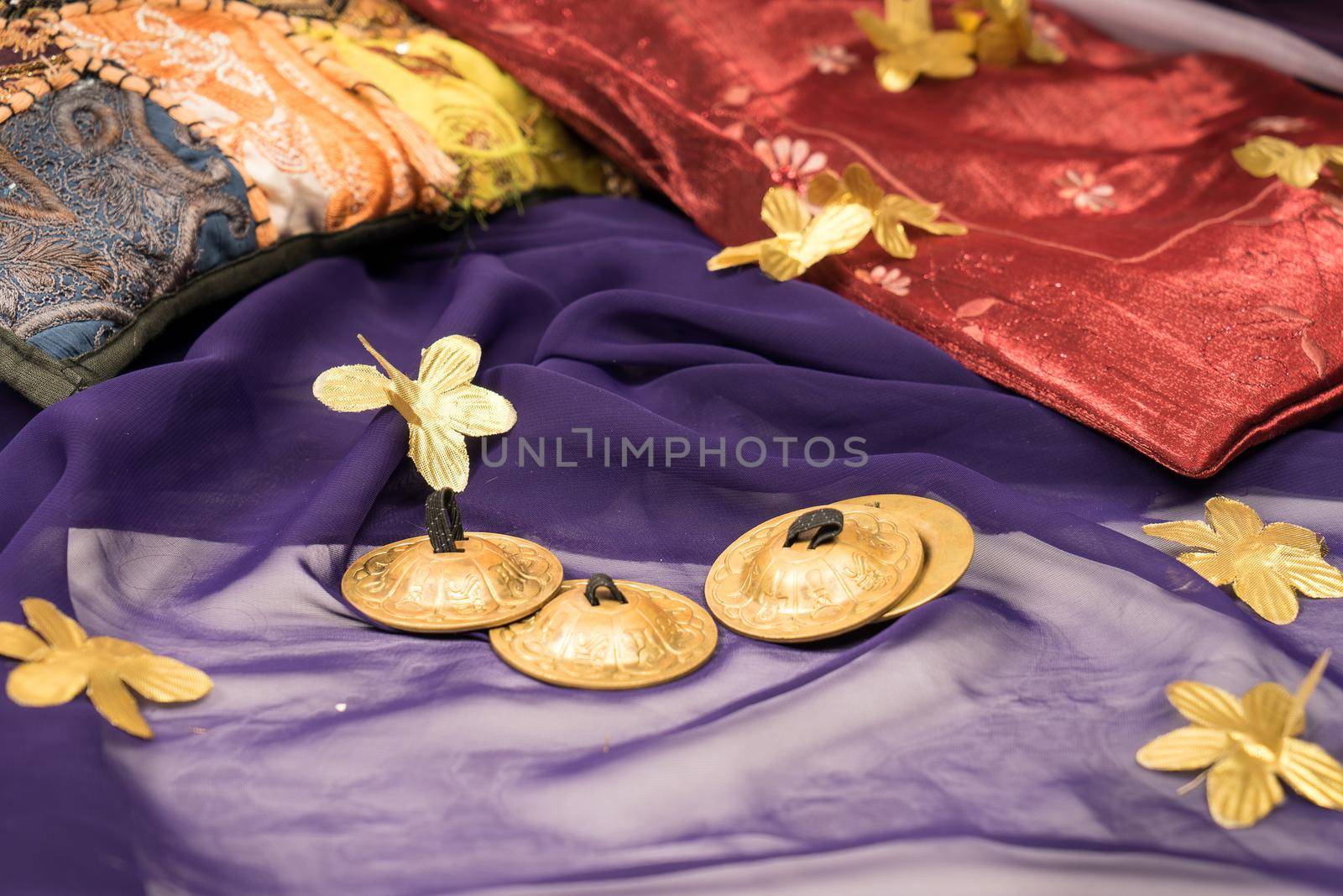 Close-up of zills for bellydancing on a purple veil with arabic cushions  by LeoniekvanderVliet