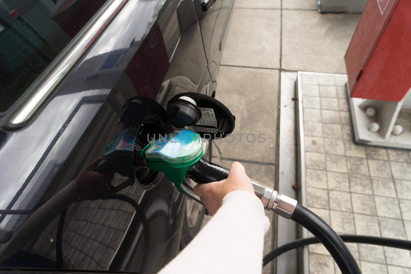 Female hand fill gasoline in a car with gas pump nozzle by LeoniekvanderVliet