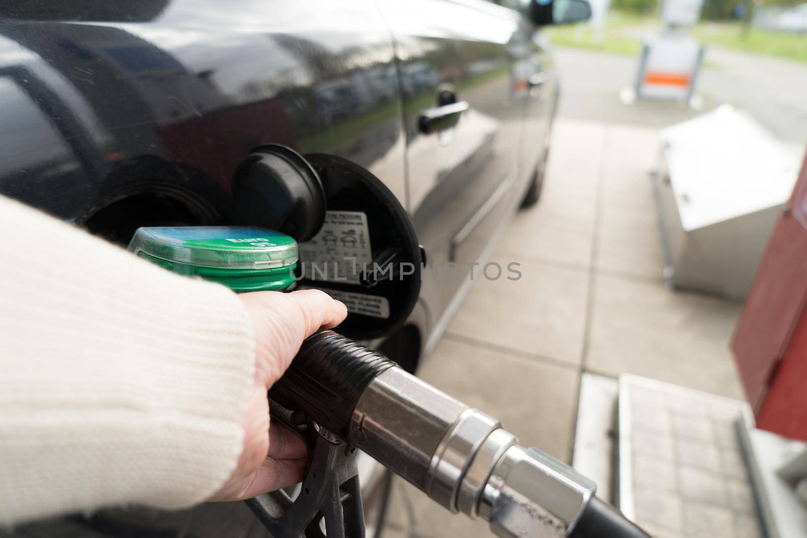 Female hand fill gasoline in a car with gas pump nozzle