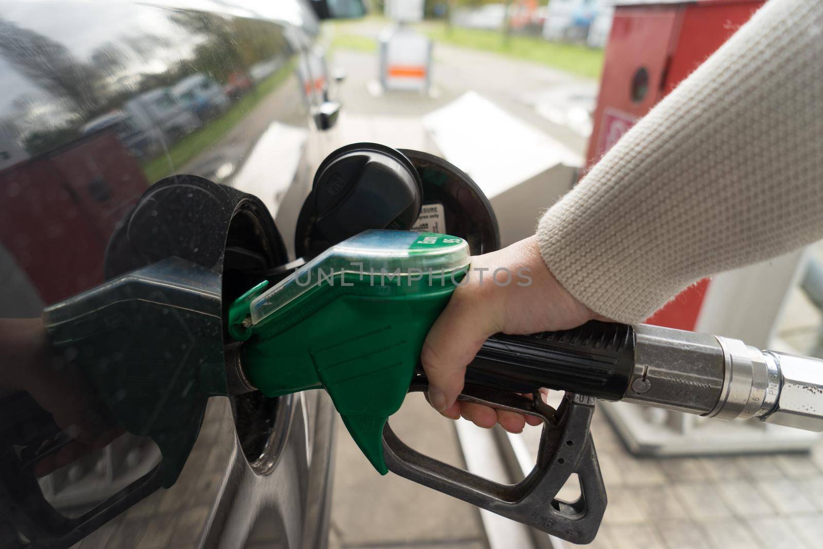 Female hand fill gasoline in a car with gas pump nozzle by LeoniekvanderVliet