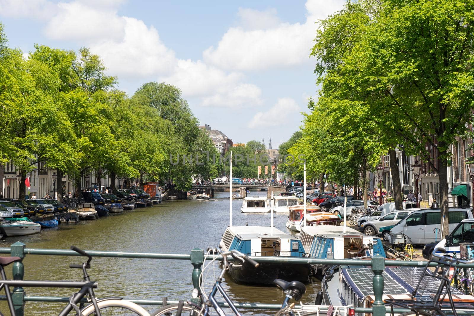 View from a bridge on the canals in Amsterdam with traditional houses, boats, bikes, trees and water in the Netherlands