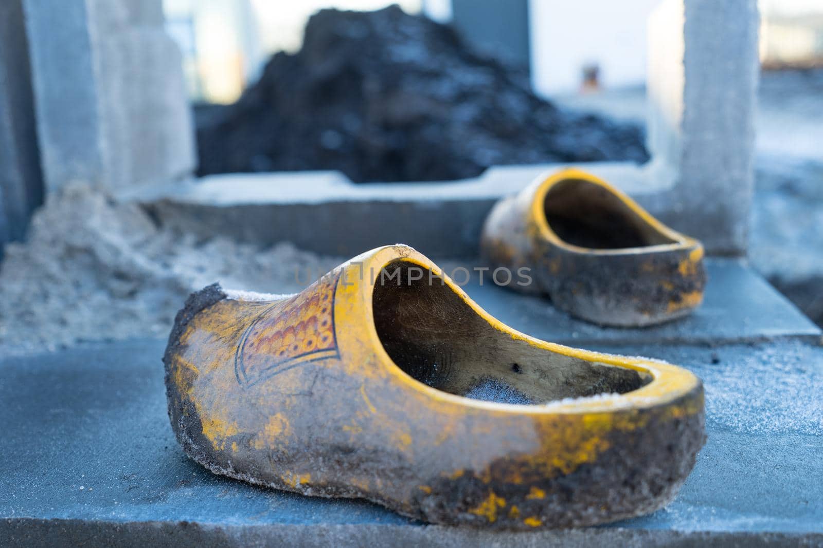 Traditional Dutch wooden shoes clogs used at a construction site with clay and dirt on them by LeoniekvanderVliet