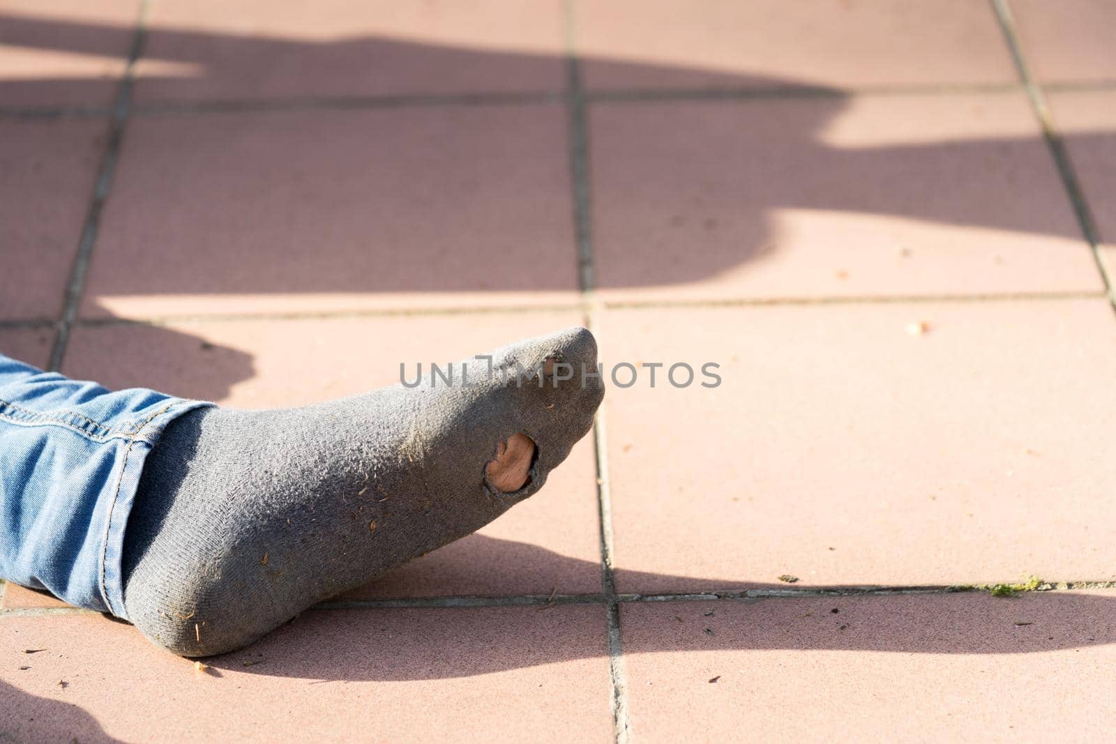 Boys foot with jeans and sn old sock with a hole in it outside