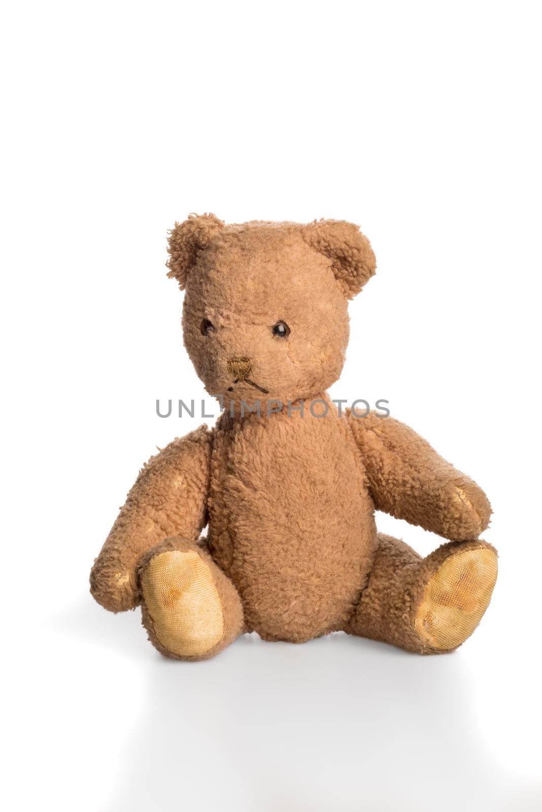 Old worn down teddy bear sitting isolated in white by LeoniekvanderVliet