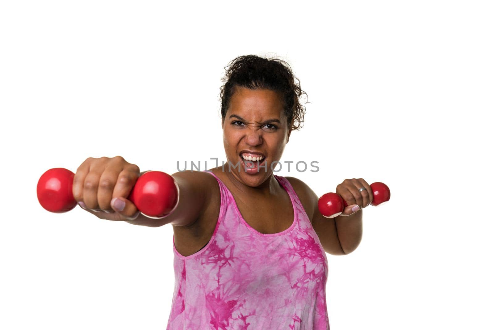 Mixed raced young woman  in pink shirt exercising with red 2 kg weights dumbbells isolated in white by LeoniekvanderVliet