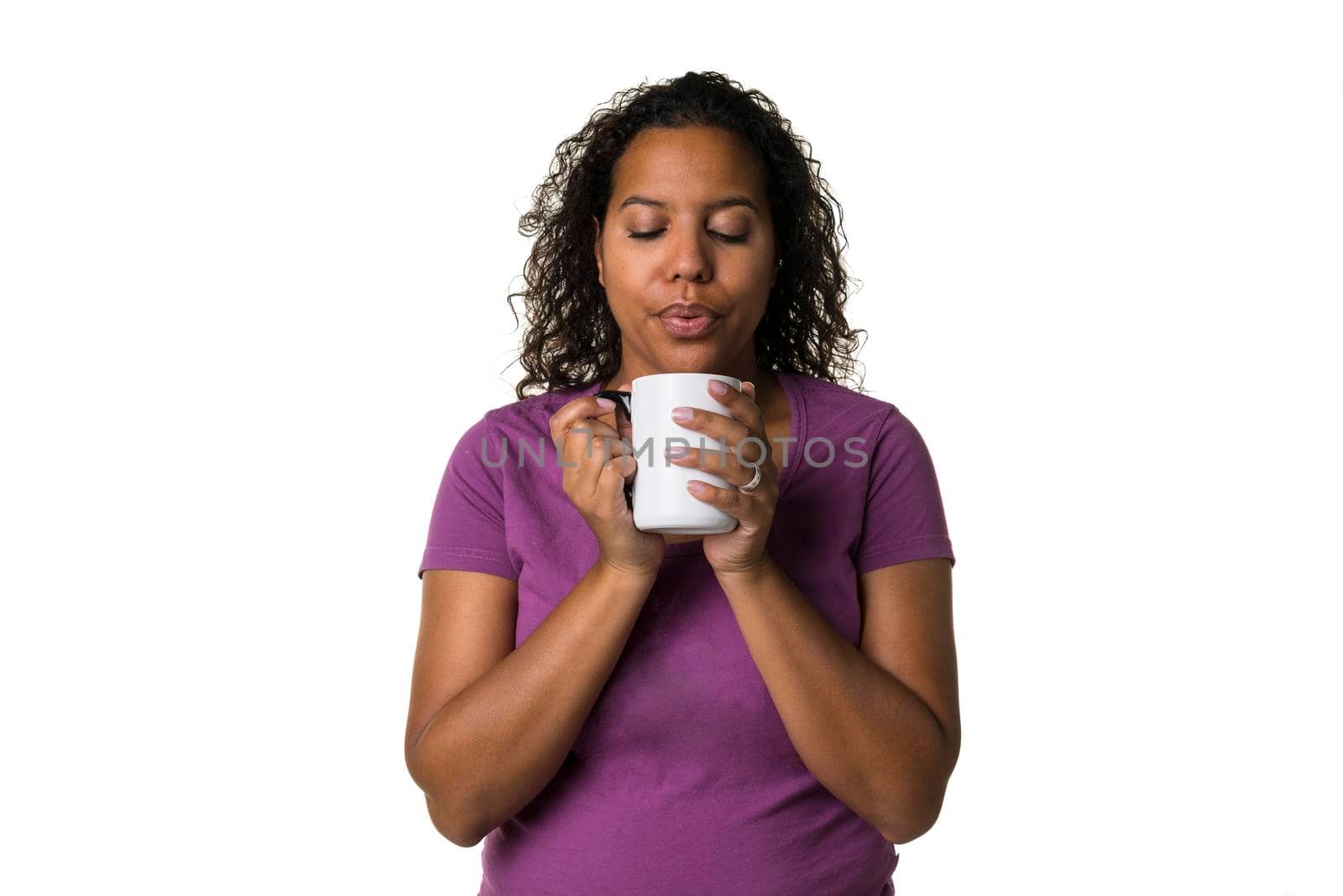 Young mixed race woman in purple shirt drinking a hot liquid from a black and white cup isolated with a white background